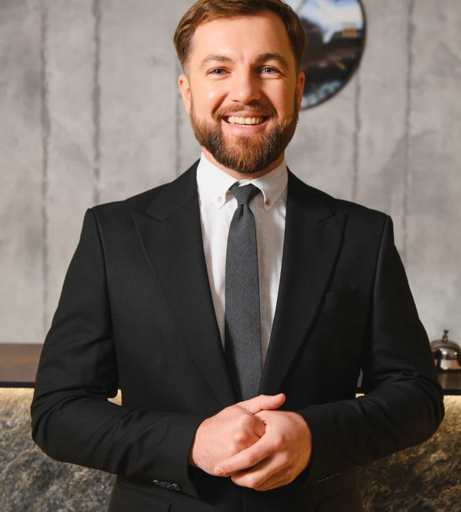 smiling-hotel-receptionist-standing-at-reception